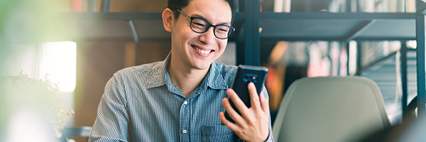Homme souriant tenant et regardant un appareil Android.